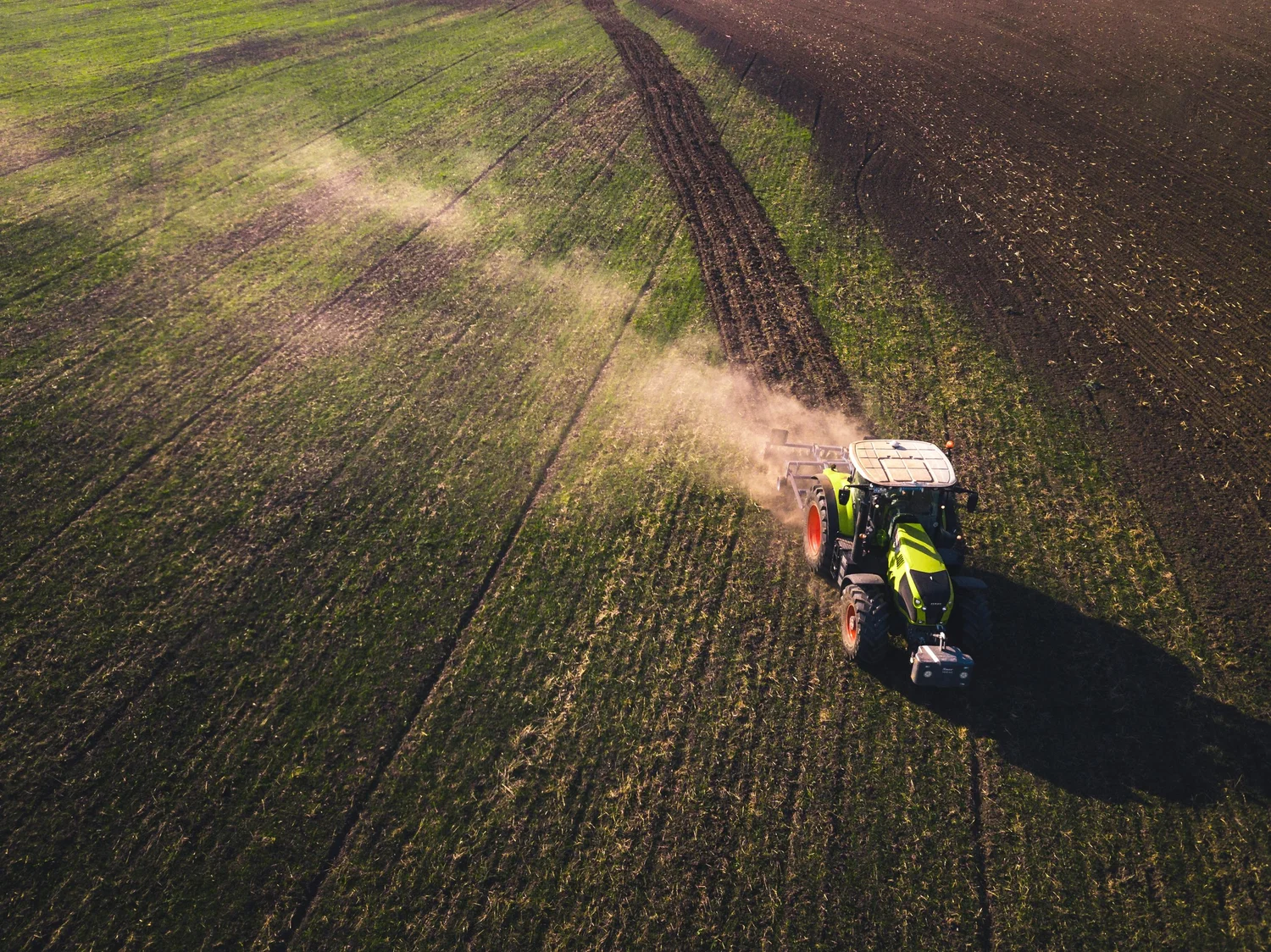 Aerial view of a tractor working agricultural fields at golden hour